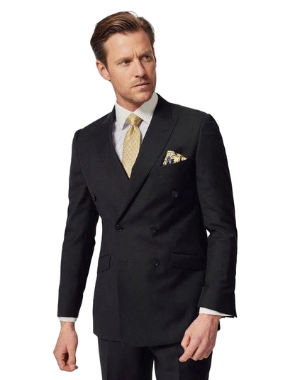 Man wearing a black suit with a white shirt and yellow tie on a light gray background