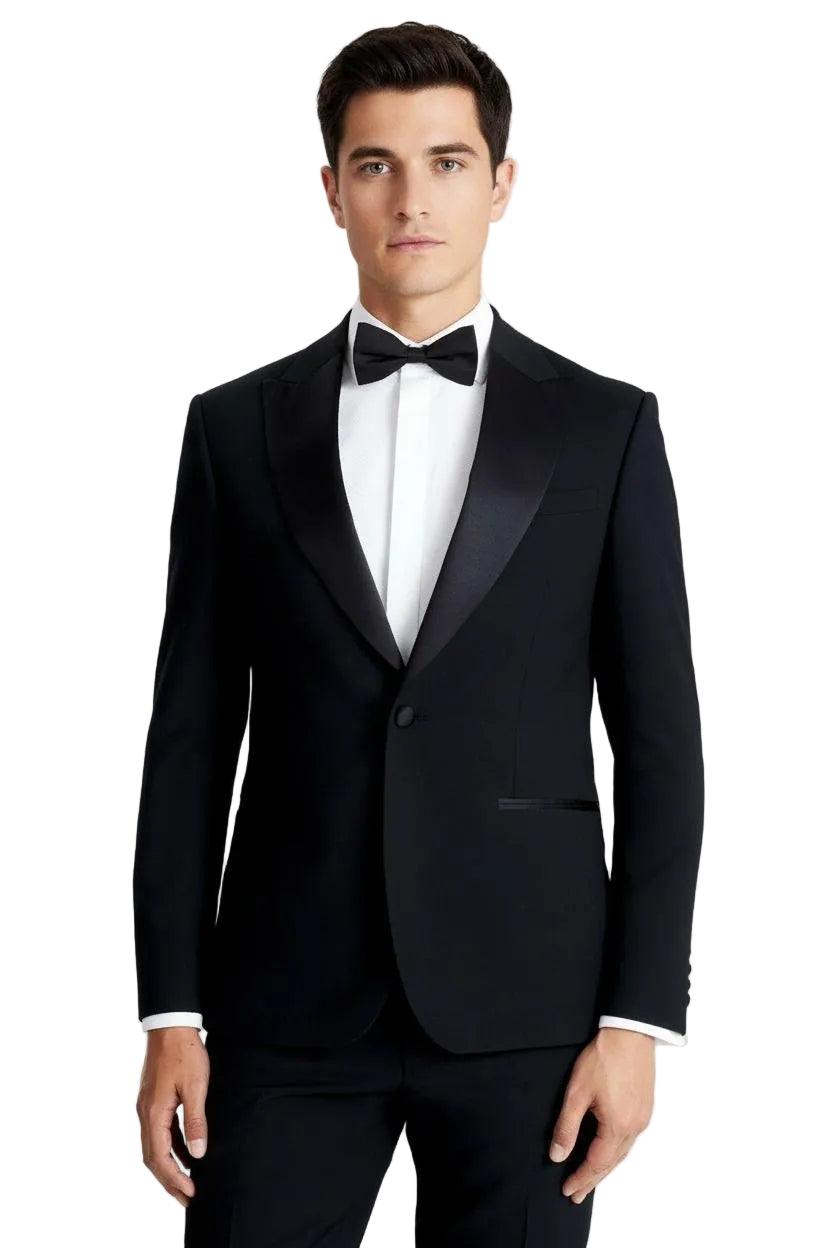 Man wearing a black tuxedo with a white shirt and black bow tie on a light gray background